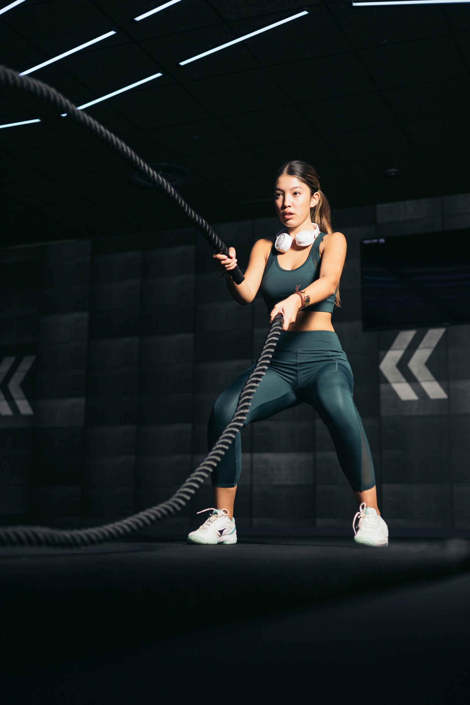 Athletic Asian woman training with battle rope in gym