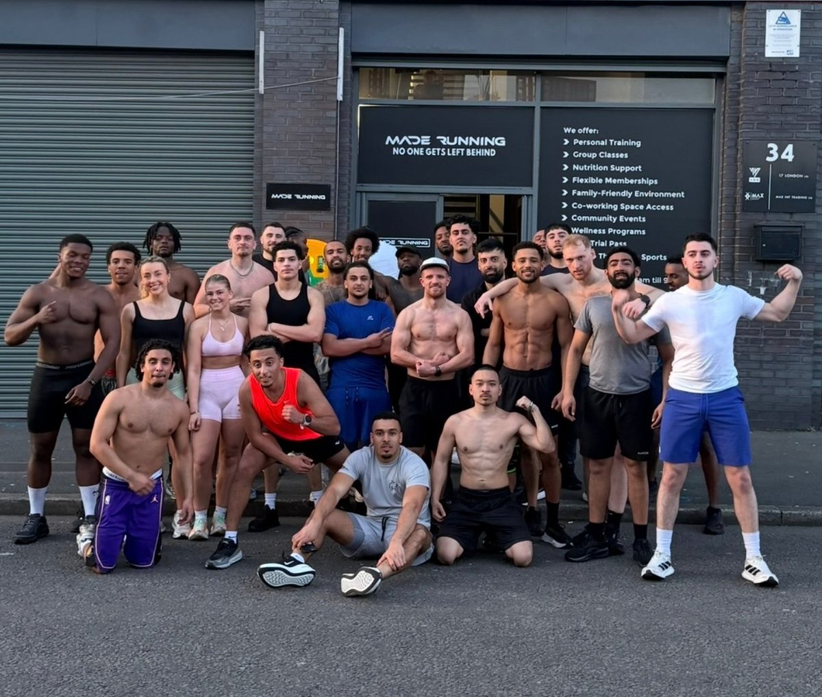 Group of fitness enthusiasts posing outside a gym, displaying athletic builds and workout attire